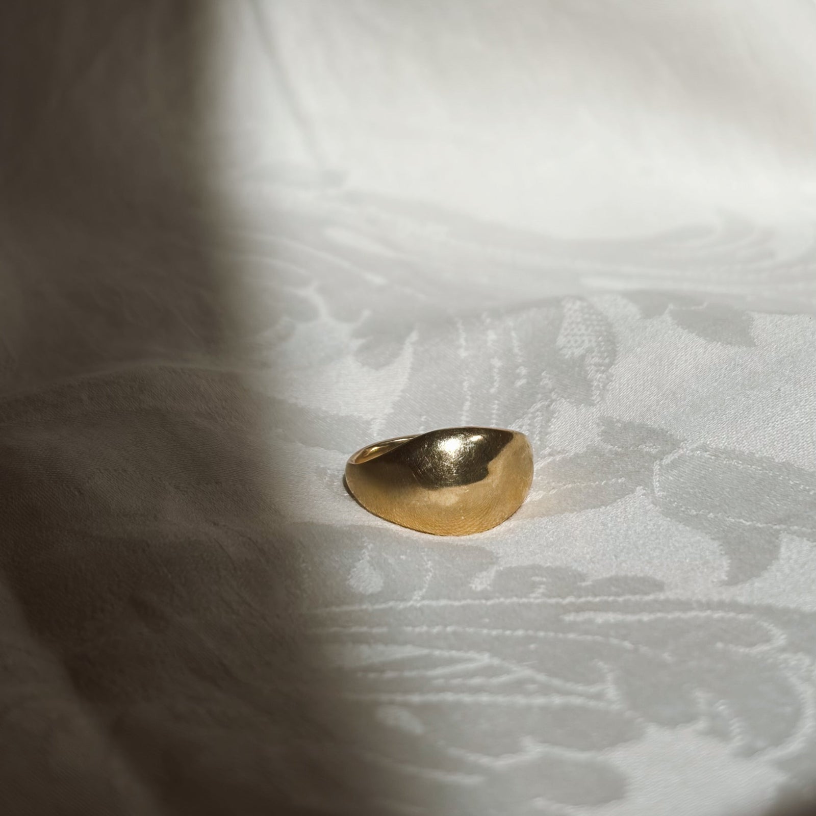 Gold ring on a textured white fabric background